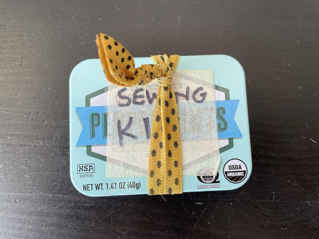 Luna's DIY travel sewing kit tin with elastic hair tie around it to show how it stays secure and shut