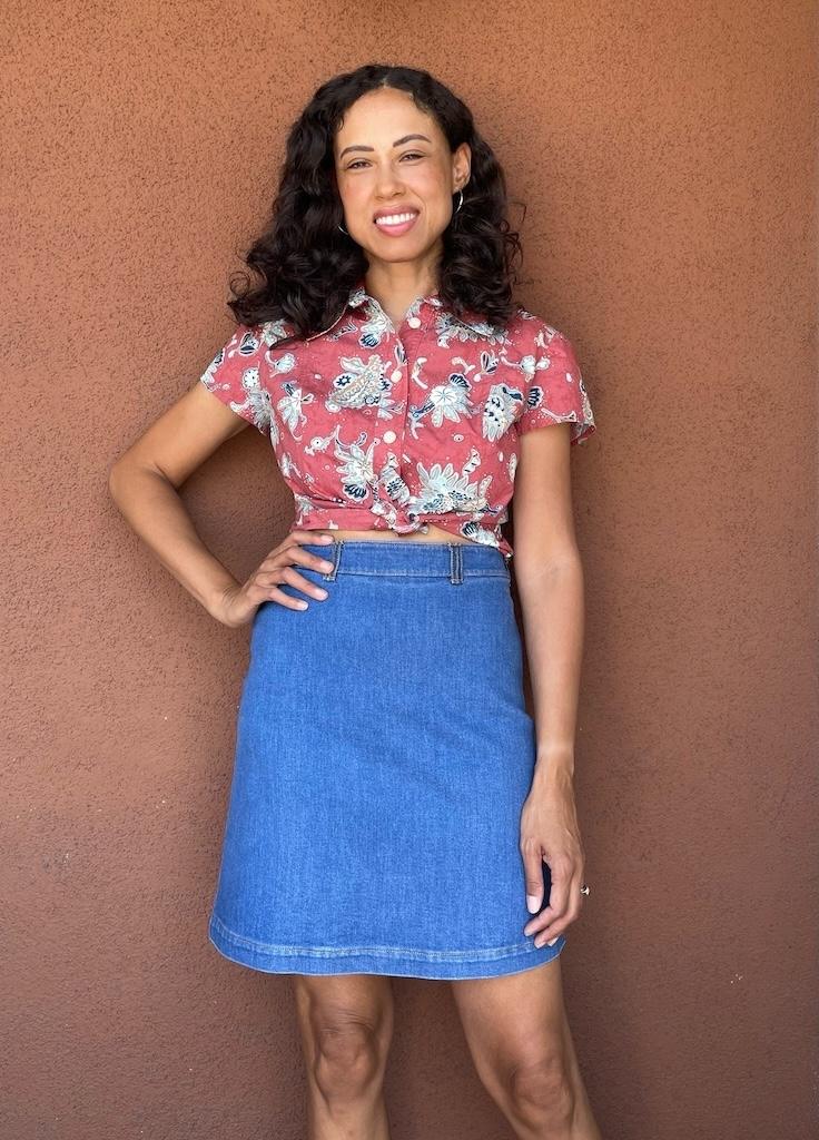 Luna wearing button up shirt and diy denim mini skirt, smiling to the camera with hand on hip
