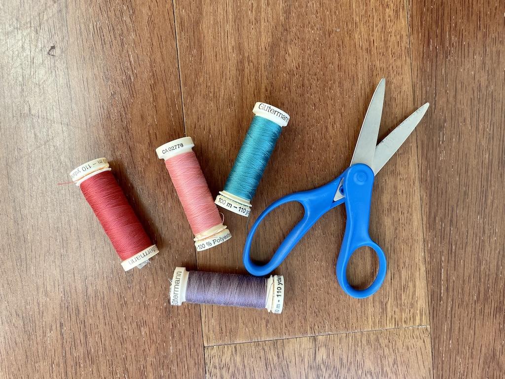 Children’s scissors with spools of thread on wooden floor