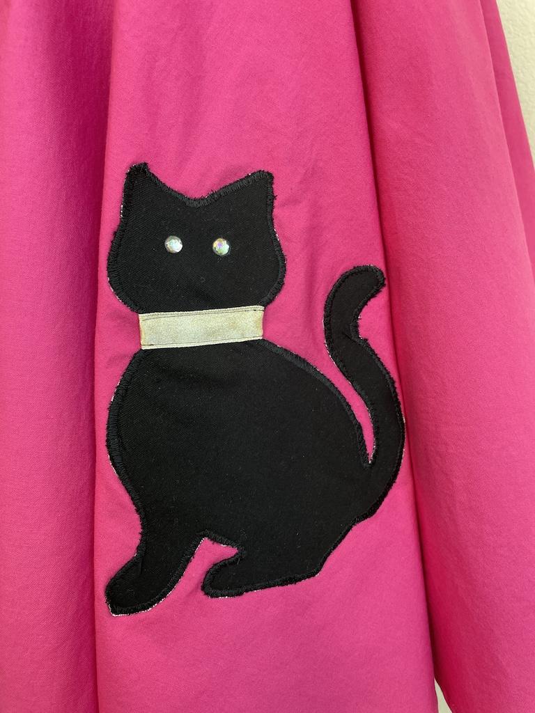 Close up of DIY cat appliqué with a gold collar and sew-on rhinestones for eyes on Luna’s handmade sock hop skirt 
