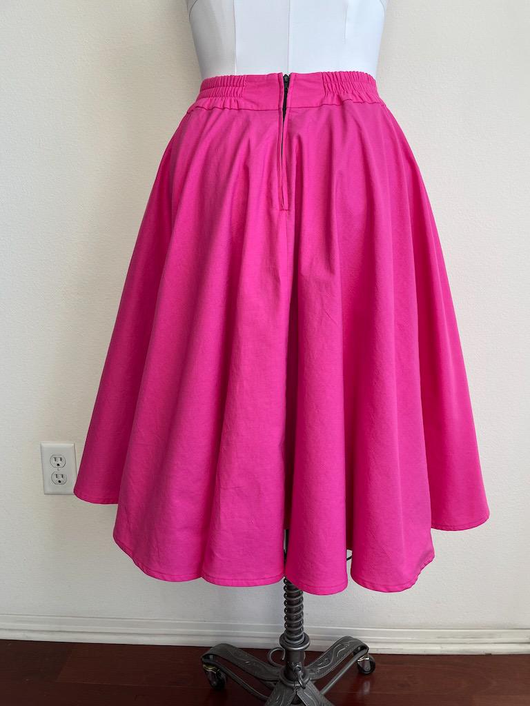 Back view of Luna’s DIY sock hop skirt in bright pink fabric with zipper opening at the waist, fitted on the dress form