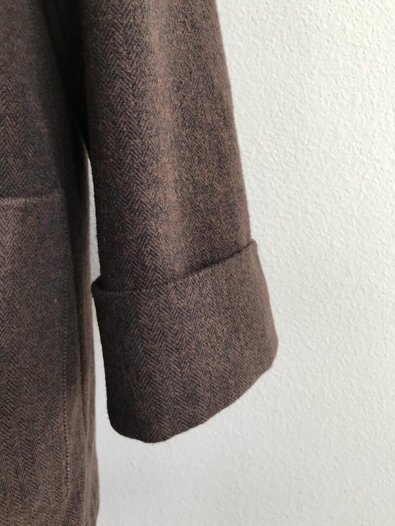 Close up of the sleeve cuff of Luna’s cardigan coat, in brown cotton woven fabric