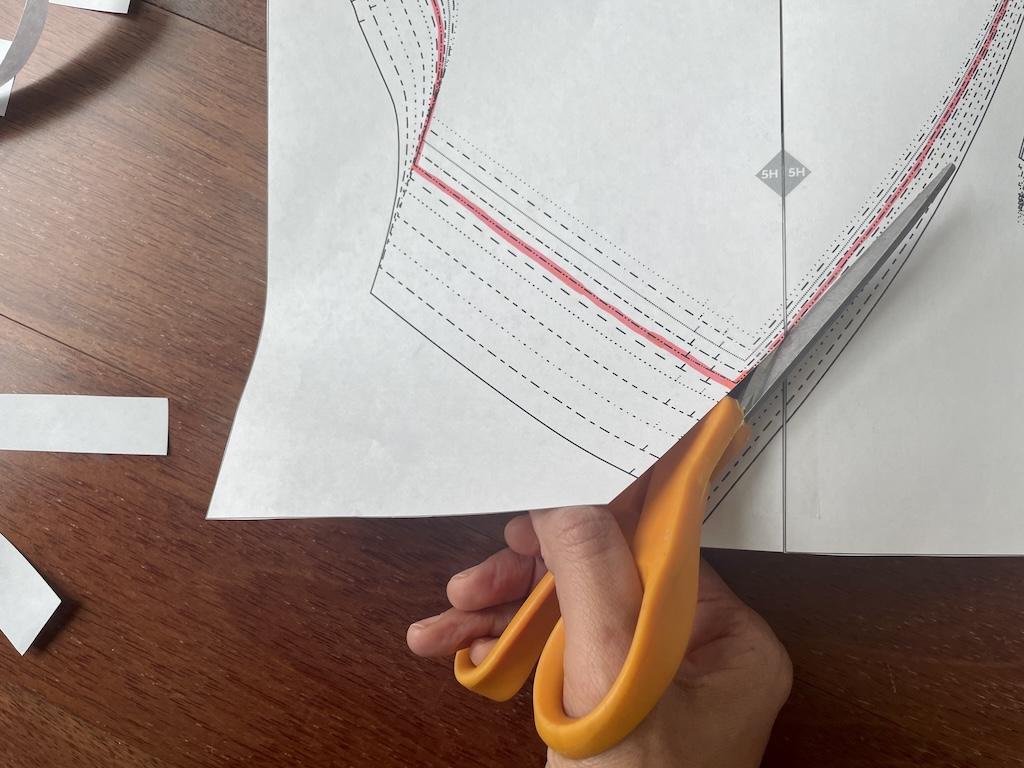 Close up of Luna’s hand cutting her highlighted size on PDF pattern 