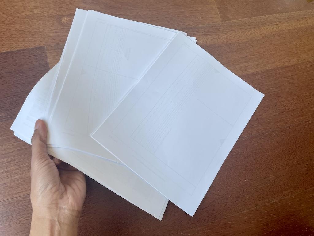 Luna’s hand holding a stack of PDF sewing patterns on floor of Sewing Room.