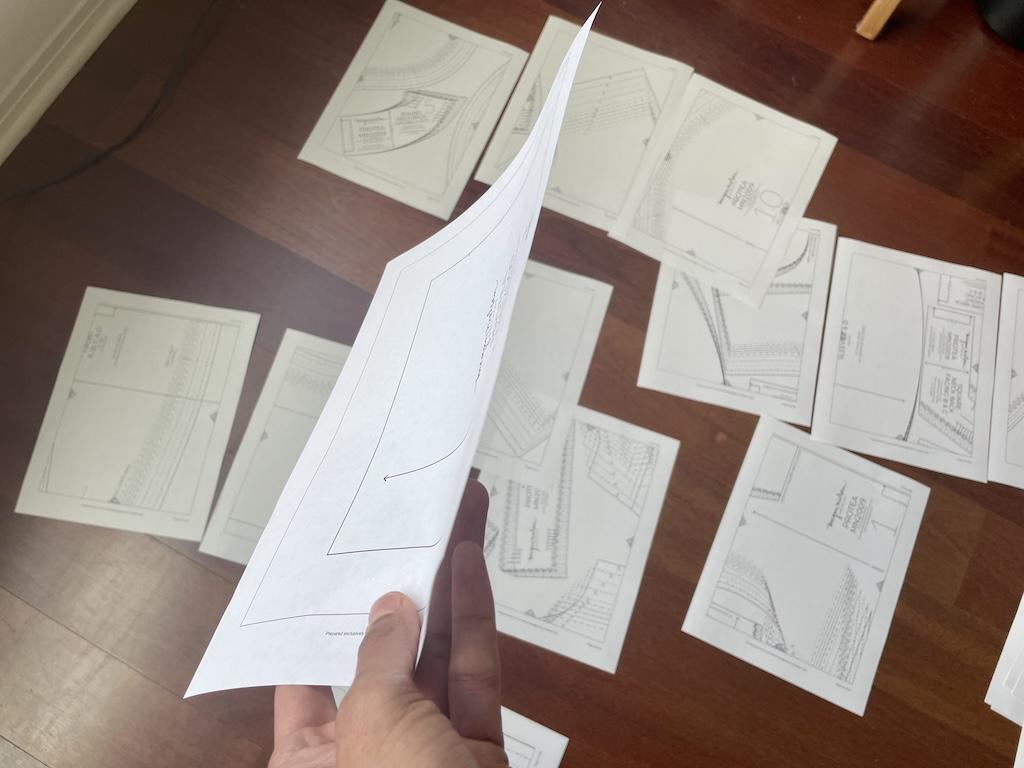 Close up of Luna’s hand holding one paper of printed digital pattern and sorting pages on the floor 