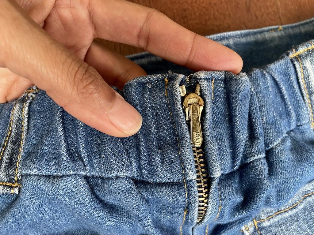Close up on the zipper and back construction of Luna’s denim skirt showing the waistband and carriers