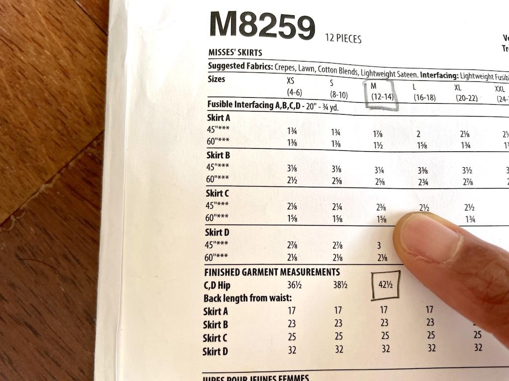 Back of McCall’s learn to sew pattern and Luna’s finger pointing to the yardage needed to make the skirt 