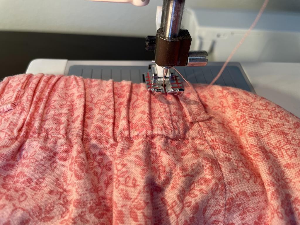 Close up view of Luna sewing the elastic into the casing of her wrap skirt with the sewing machine