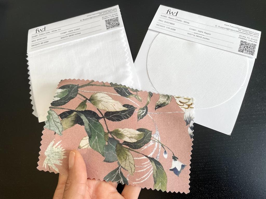 Close up of Luna’s hand holding her DIY fabric swatch with others from a store in the background