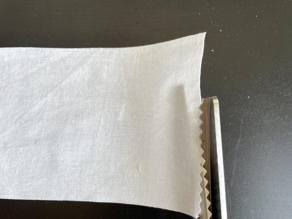 Close up view of Luna’s pinking shears finishing edge of fabric swatch by cutting