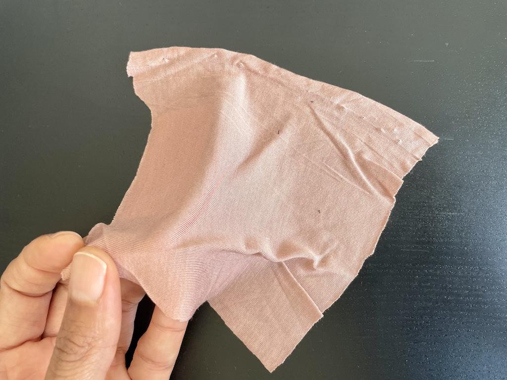 Close up of Luna’s hand holding a knit fabric swatch