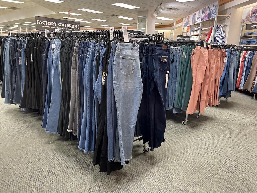 Factory overruns of pants and jeans on clothes racks in an outlet store that Luna saw while shopping
