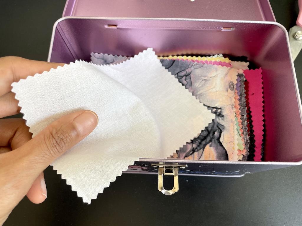 Close up of Luna’s hand putting fabric swatch in her old lunch box