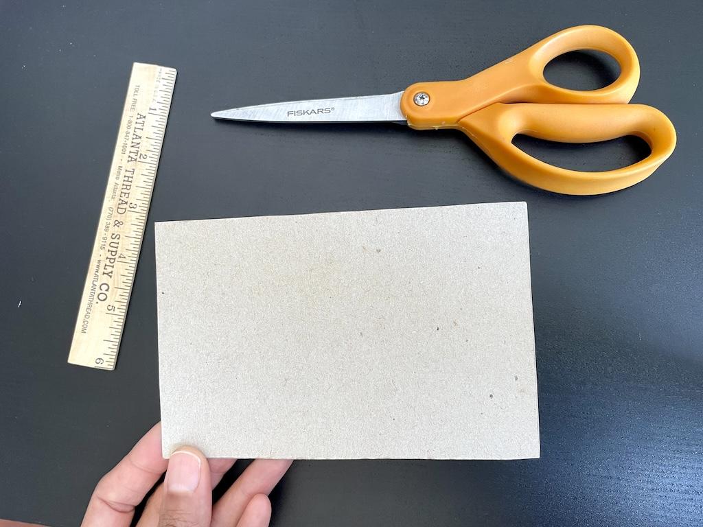 Close up of Luna’s hand holding her cardboard template to make fabric swatches