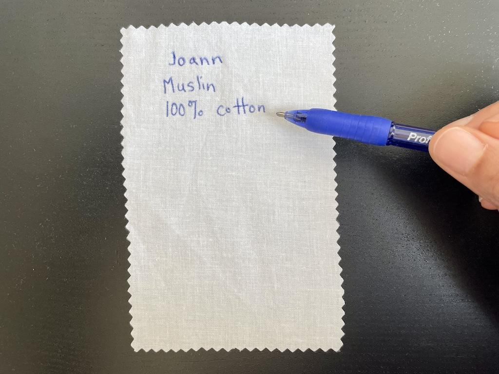Close up of Luna’s hand holding ink pen and writing fabric information on swatch