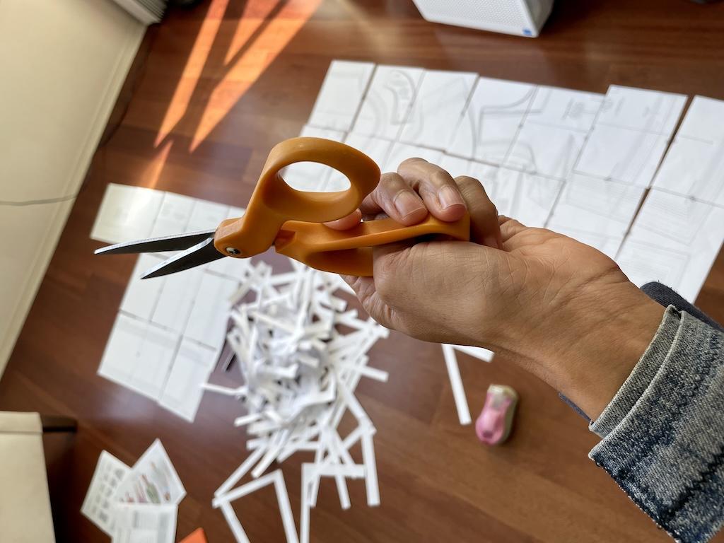 View of Luna’s hand holding scissors and cut sewing patterns in the background