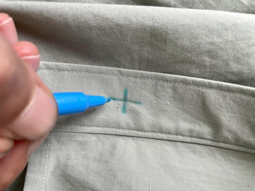 Close up view of Luna drawing cross marking for sewing buttons on shirt