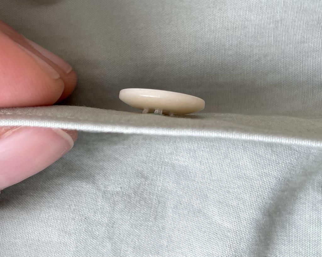 Close up side view of Luna’s fingers and hand sewn button on her DIY shirt