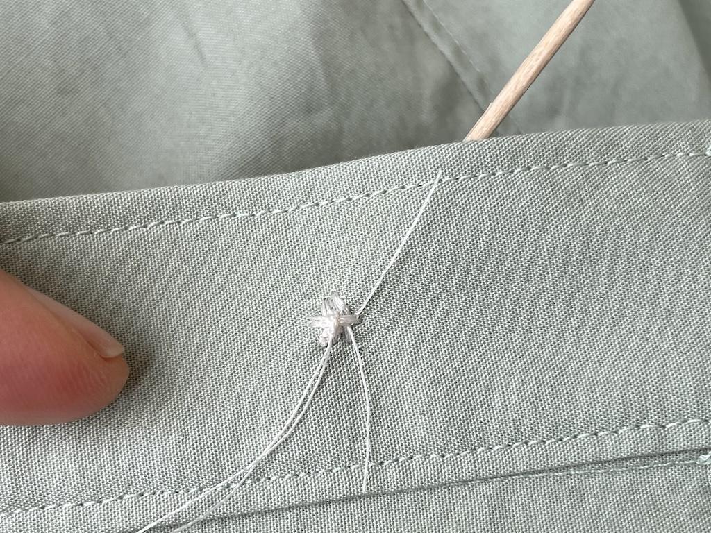 Close up of knot made on stitches on back side of fabric of button Luna hand sewed