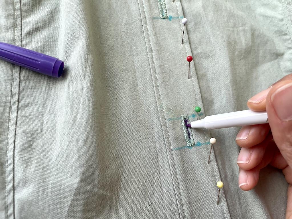 Close up view of Luna’s hand marking the button placement on DIY shirt with water soluable marker