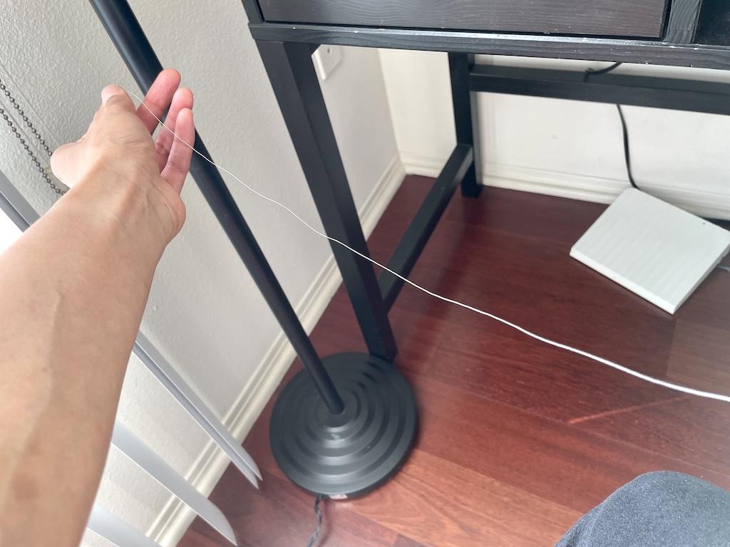 View of Luna’s arm pulling thread out to measure for handsewing button on shirt