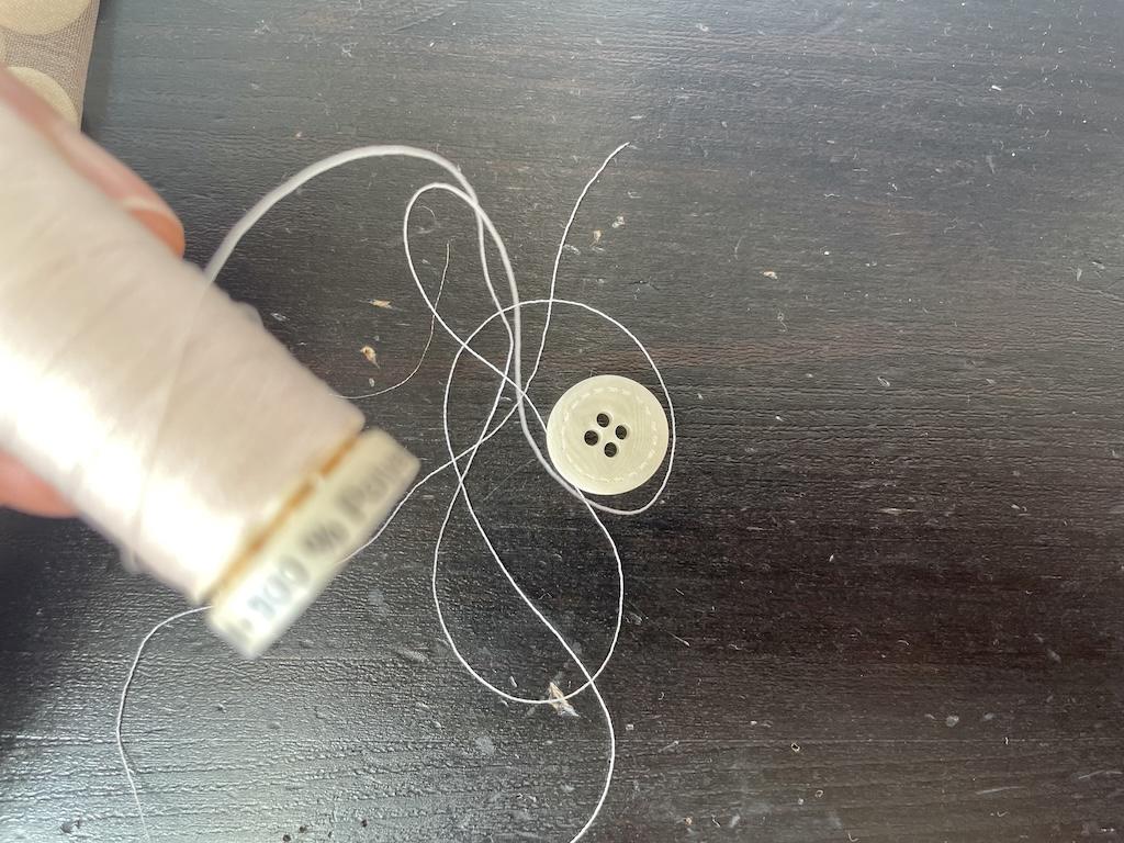Close up view of thread and button for handsewing on shirt