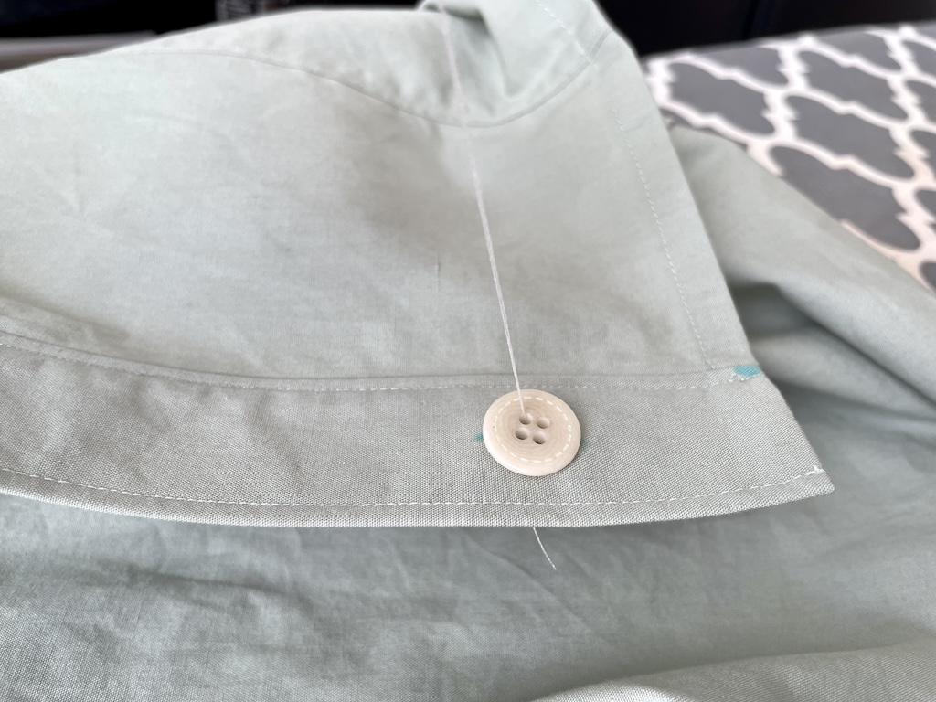 Close up view of button on marking on shirt with thread through hole