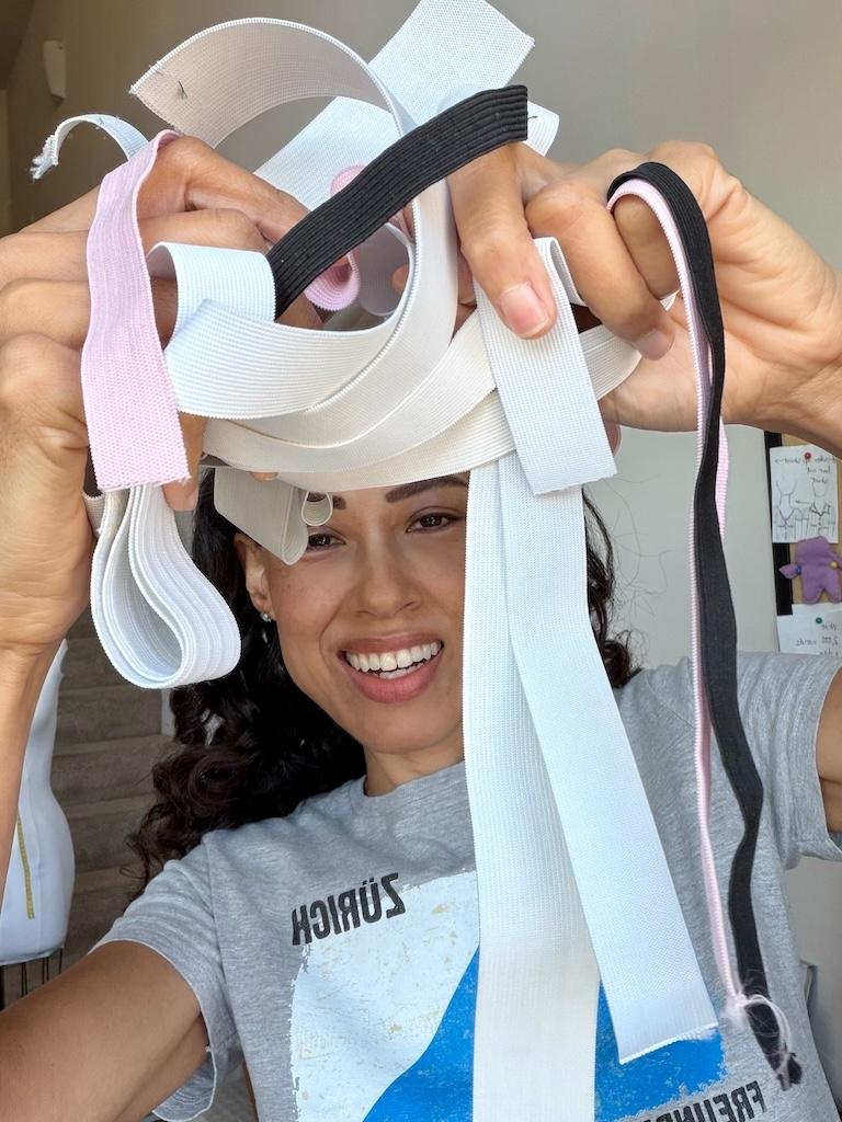 Luna smiling to the camera holding up common types of elastic used for sewing