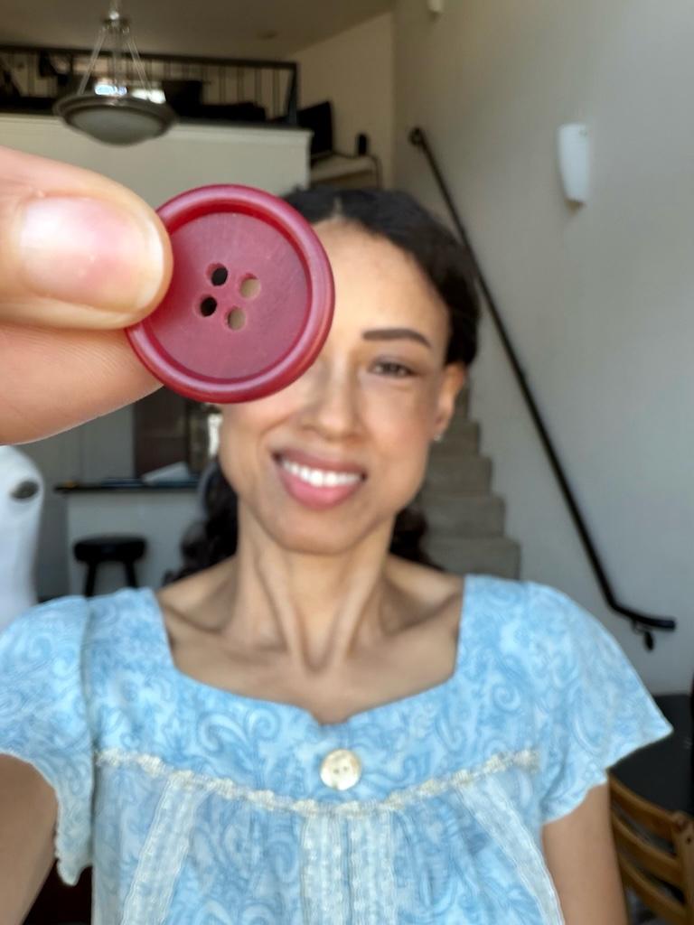 Luna smiling and holding up 4-hole button to camera