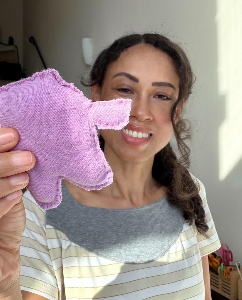 Luna smiling and holding up a small stuffed animal beginner sewing project
