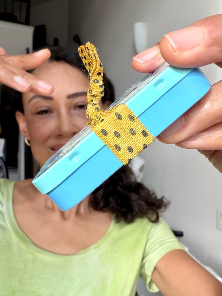 Luna smiling and showing the side view of her mini DIY travel sewing kit that she made