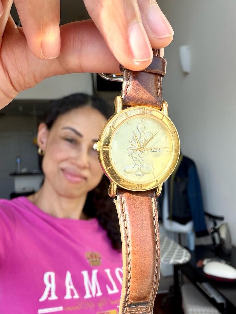 Luna holding up her Mickey Mouse watch in her sewing room