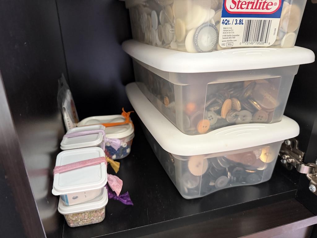 View of Luna’s buttons stored in clear plastic shoe boxes in cubbie in her sewing room