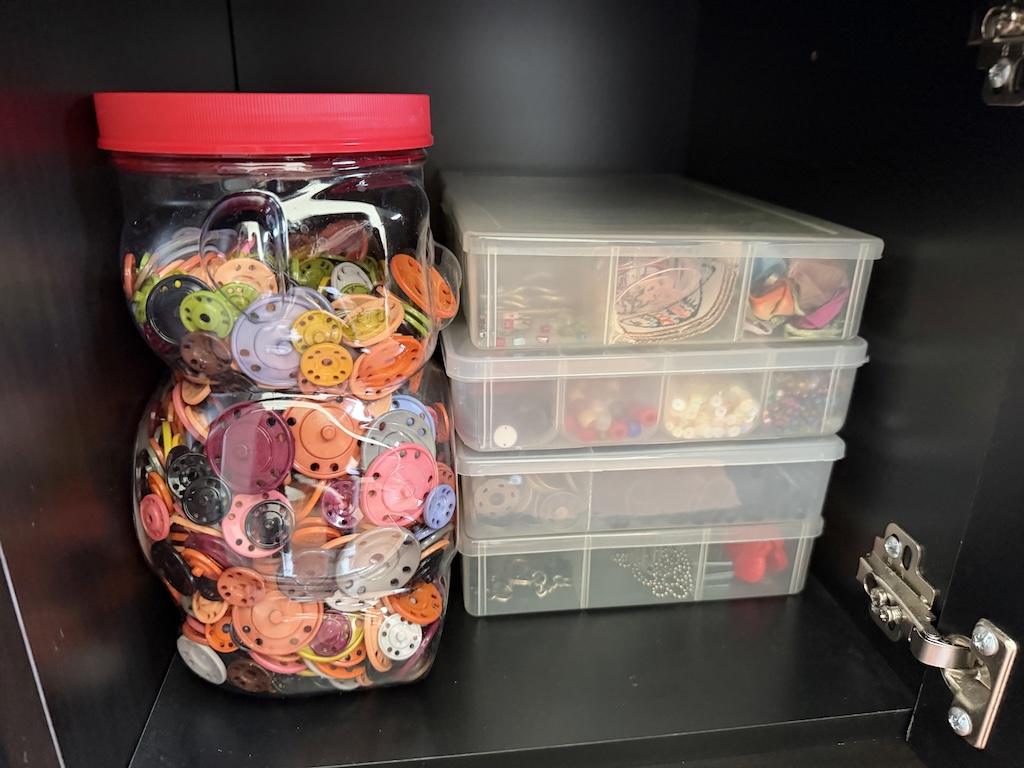 View divided plastic craft containers in cubbies Luna uses in sewing room