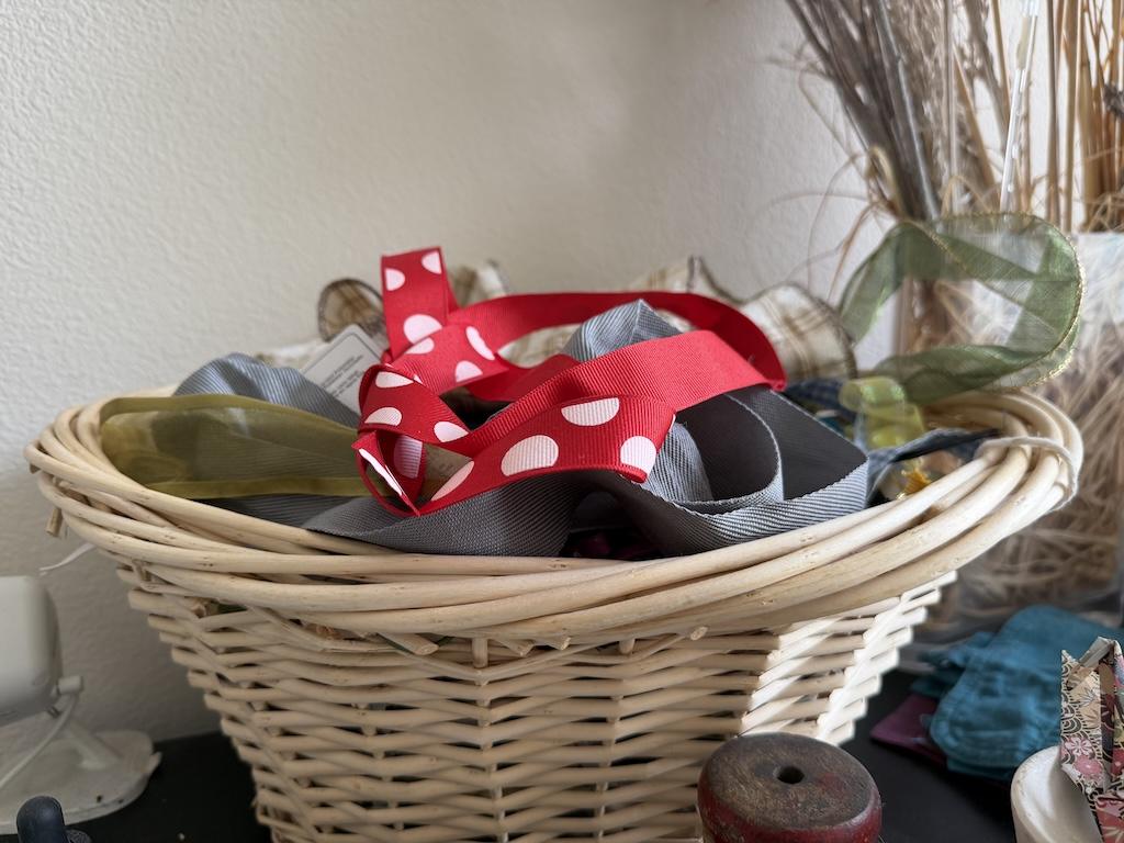 View of woven basket Luna uses in her sewing room with ribbons