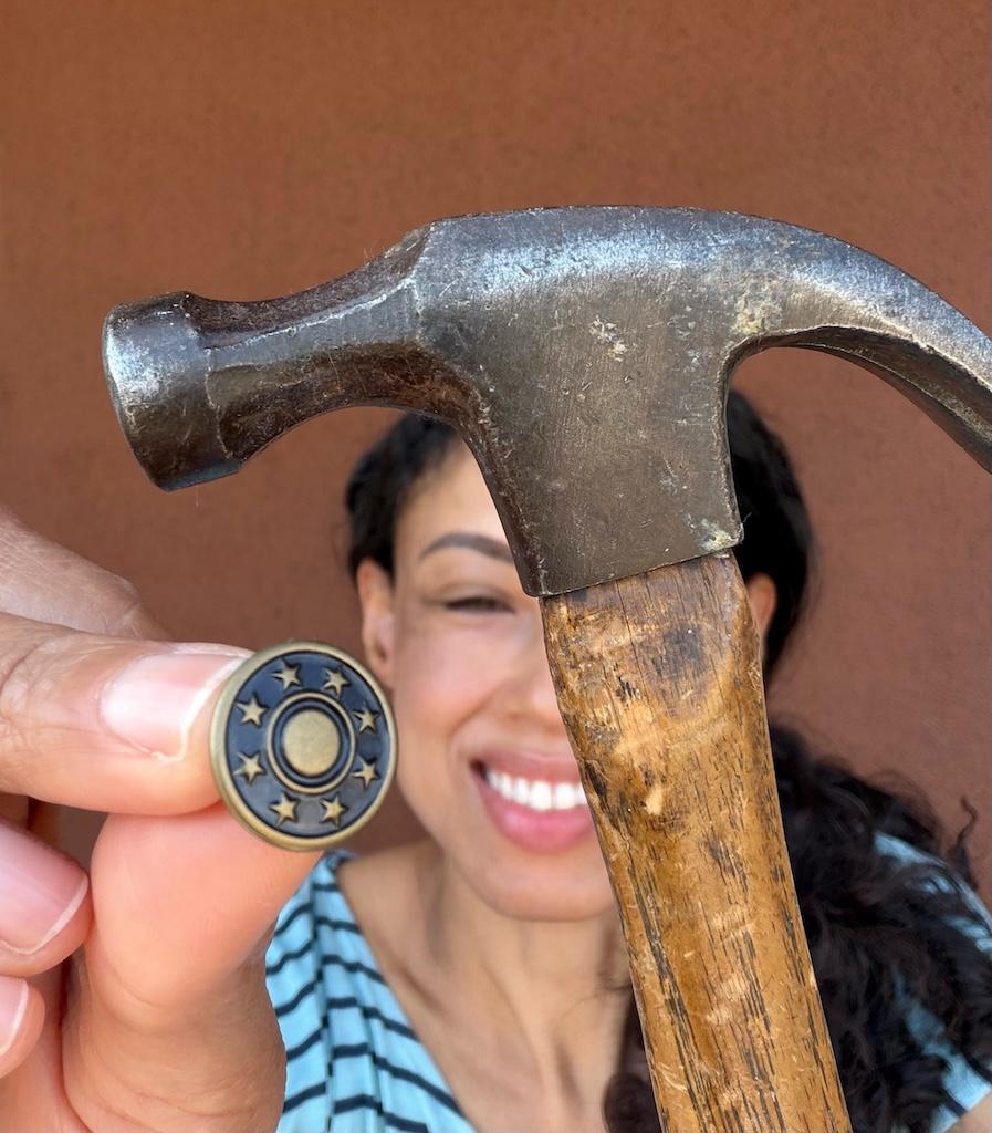 Close up of jeans button and hammer Luna is holding while smiling in the background