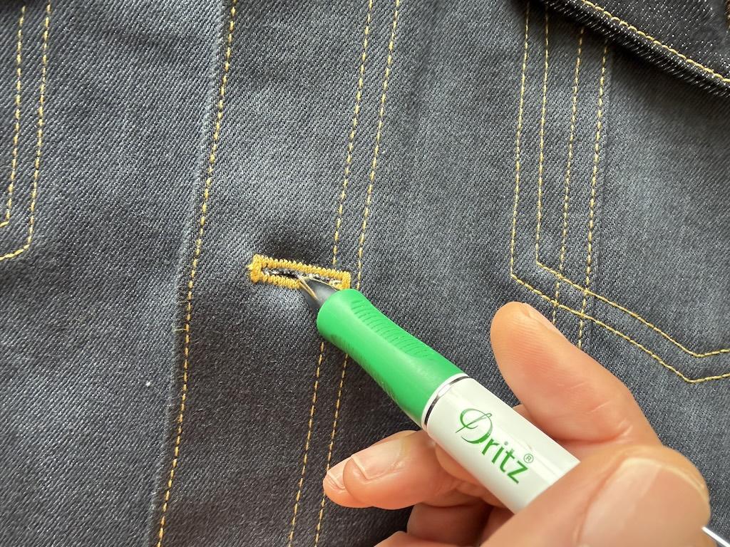Close up view of Luna’s hand marking the button placement of the jeans button on her denim jacket she made