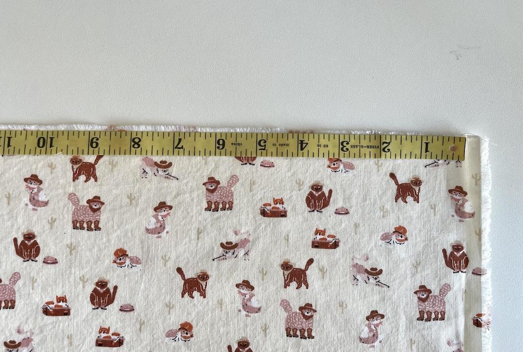 Close up of measuring tape across quilting cotton on cutting table