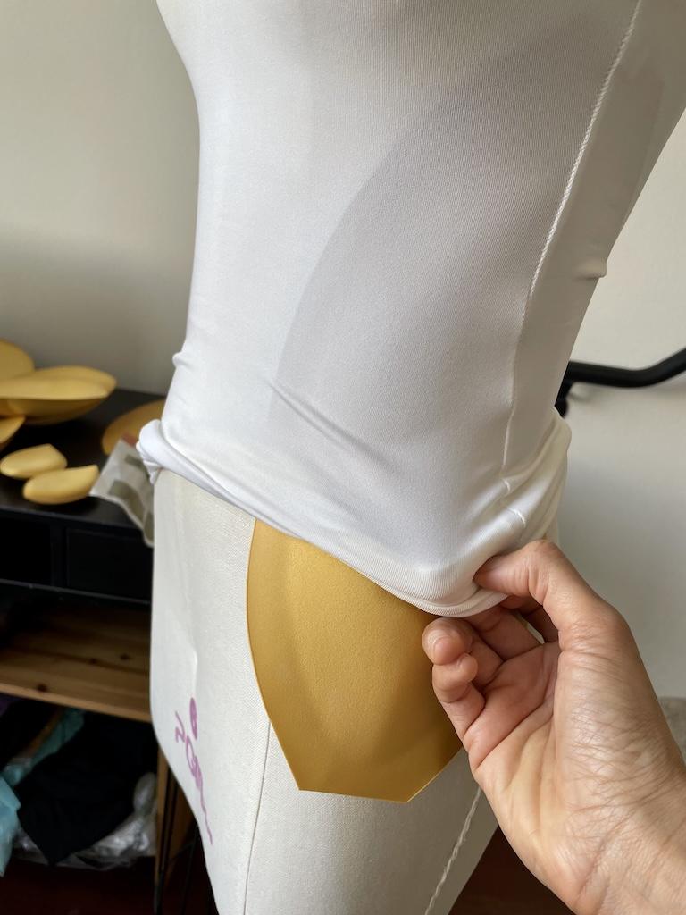 Side view of Luna’s hand adding padding to dress form