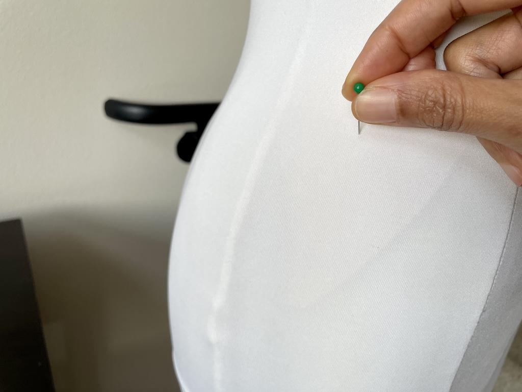 Close up of Luna’s hand pinning dress form after she padded it