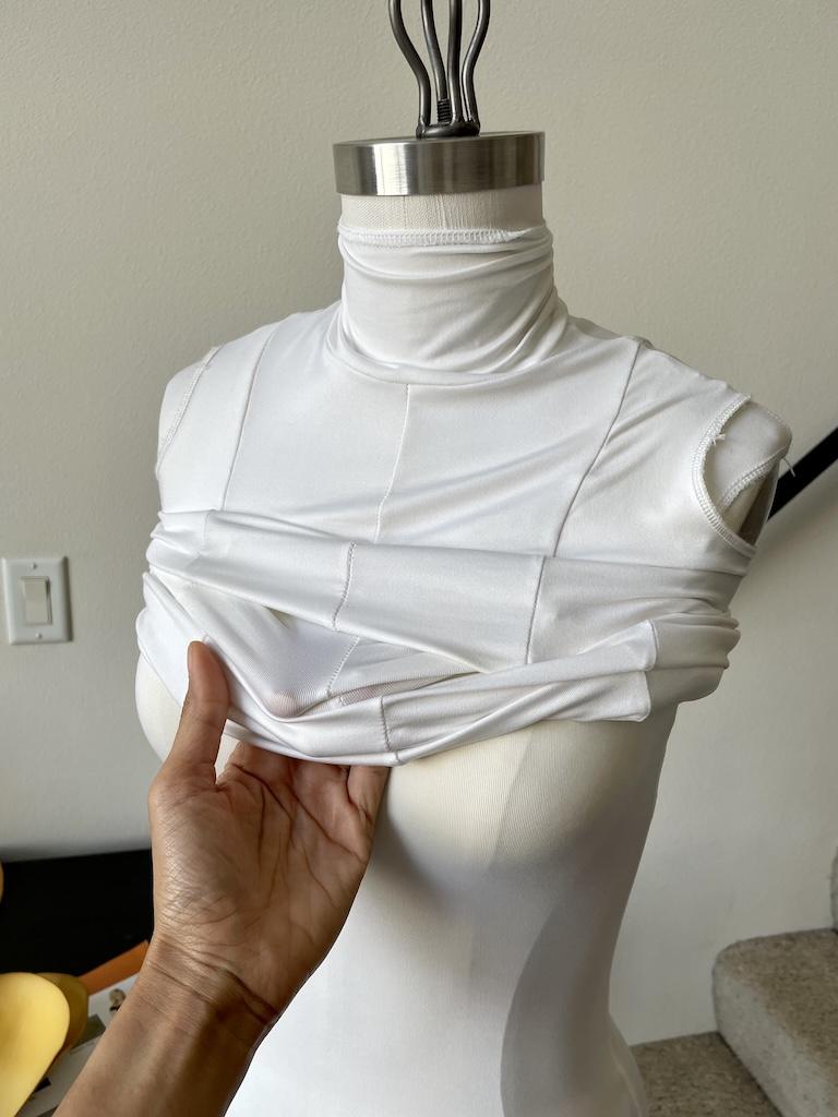 Luna’s hand rolling on top bodysuit on dress form after she padded it