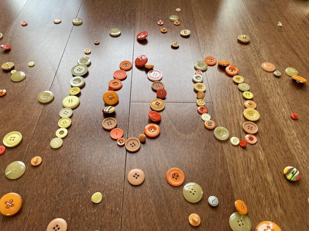Buttons spelling out 100 on Luna’s wooden floor